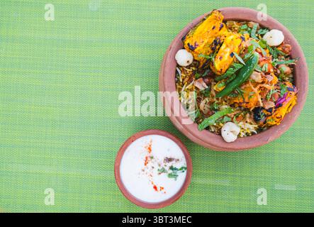 Paneer Biryani di verdure in una ciotola di terra servita con raita e condimenti di yogurt, ristorante indiano a Dubai, ricetta vegetariana per cena a base di piante Foto Stock