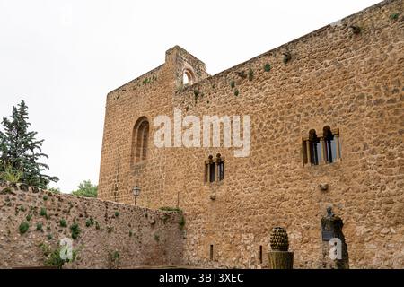 I visitatori potranno ammirare le antiche mura di pietra di un castello a Brihuega, Guadalajara. La struttura presenta caratteristiche architettoniche uniche su un cielo grigio Foto Stock