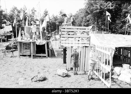 Costruzione capanna Herenweg Herenweg, Whizgle News, Dutch Desk, Paesi Bassi, 1950 - 2000 il 07-08-1996. L'immagine mostra questi argomenti. La scena è piena di attività, ambientata in un'area all'aperto che presenta diverse strutture improvvisate, probabilmente un'area giochi informale o un incontro della comunità. Le strutture, costruite con tavole e casse di legno, mostrano segni di creatività e immaginazione, con una varietà di forme e altezze. Alcune sono dipinte in colori vivaci, mentre altre conservano una finitura in legno naturale, donando alla scena un'atmosfera giocosa ma rustica. Un gruppo di bambini è impegnato in una diversa a Foto Stock