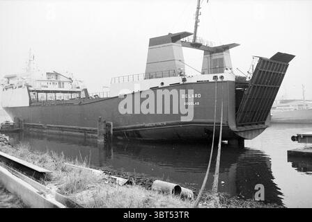 Cargo The Belard, Whizgle News, Dutch Desk, Paesi Bassi, 1950 - 2000 il 22-11-1993. Questi argomenti vengono visualizzati nell'immagine. La scena presenta una grande nave ormeggiata in un porto, che mostra in modo prominente uno scafo grigio-acciaio contrastato da strutture grigie più chiare sopra. Il design della nave presenta angoli netti, con una silhouette imponente che suggerisce uno scopo pratico. Intorno all'imbarcazione, l'acqua appare scura e calma, riflettendo il profilo della nave e i colori tenui. Una leggera nebbia è appesa nell'aria, creando un'atmosfera soffusa che contribuisce a creare un senso di quiete e tranquillità. La luce Foto Stock