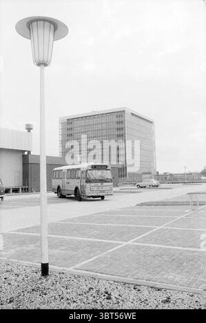Report NZH Leiden Noord Zuid Hollandse Vervoersmaatschappij N.V. NZ, Whizgle News, Dutch Desk, Paesi Bassi, 1950 - 2000 il 25-10-1971. Questi sono gli elementi dell'immagine. La scena cattura un aspro paesaggio urbano caratterizzato da una miscela di elementi moderni e un po' datati. In primo piano, un autobus d'epoca mostra chiaramente il suo profilo mentre si sposta lungo una superficie asfaltata, passando da un parcheggio a una strada. Il suo design richiama un'epoca passata, con bordi arrotondati e grandi finestre che riflettono l'ambiente circostante. Accanto all'autobus, si erge un lampione alto che emette un muto Foto Stock