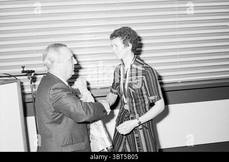 Cerimonia di premiazione del baseball Baseball, Whizgle News, Dutch Desk, Paesi Bassi, 1950 - 2000 il 15-11-1981. L'immagine mostra questi argomenti. La scena cattura un momento formale, probabilmente durante una cerimonia di premiazione o un evento simile. A sinistra si erge un uomo anziano, vestito con un abito, caratterizzato da una giacca scura e da una camicia di colore chiaro. La sua espressione facciale appare seria ma calda, indicando un tono di rispetto e riconoscimento. Sta estendendo la mano verso una donna a destra, suggerendo uno scambio o un saluto. La donna che indossa un abito a righe verticali che fonde sfumature di buio e labbra Foto Stock