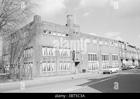 Esterno H.K.B. esterno Haarlem Tempeliersstraat Paesi Bassi, Whizgle News, Dutch Desk, Paesi Bassi, 1950 - 2000 il 17-04-1969. Questi argomenti sono mostrati nell'immagine. La scena mostra un robusto edificio rettangolare composto principalmente da mattoni con un design un po' utilitario. La facciata mostra una sinfonia di grigi e marroni, emanando un senso di permanenza e struttura. Grandi finestre rettangolari allineano la parte anteriore e i loro pannelli di vetro riflettono una luce naturale diffusa. Molte di queste finestre sono adornate con tende di colore chiaro, che suggeriscono l'attività all'interno. A sinistra, un percorso modesto Foto Stock