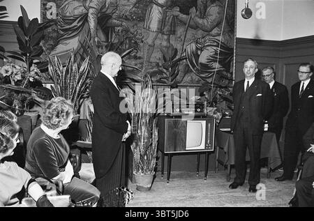 Sig. Van Wingerden, segretario municipale Heemstede Huldiging, Whizgle News, Dutch Desk, Paesi Bassi, 1950 - 2000 il 01-02-1964. L'immagine include questi argomenti. In una sala ben arredata caratterizzata da un'atmosfera elegante e vintage, un raduno di persone è impegnato nella conversazione, le loro espressioni vanno dall'attento all'allegro. L'ambiente presenta pannelli di legno scuro e alti soffitti, con un grande murale che raffigura figure o scene storiche, dando un senso di profondità e interesse allo sfondo. In primo piano, un gruppo di uomini in tute nere formali si trova vicino a un televisore t Foto Stock