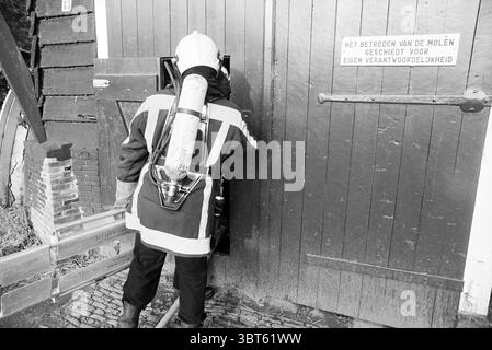 Esercitazione dei vigili del fuoco Santpoort Santpoort, Whizgle News, Dutch Desk, Paesi Bassi, 1950 - 2000 il 04-10-1993. Questi argomenti sono mostrati nell'immagine. In questa scena, un vigile del fuoco rivestito di equipaggiamento protettivo è raffigurato in un momento d'azione. Il vigile del fuoco indossa un casco bianco e un serbatoio d'aria fissato alla schiena, il che significa essere pronto per potenziali emergenze. L'attrezzatura è prevalentemente scura con strisce riflettenti che catturano la luce soffusa, migliorando la visibilità in un ambiente potenzialmente pericoloso. L'ambientazione comprende una porta rustica in legno, probabilmente intemprata e invecchiata, caratterizzata da una r Foto Stock
