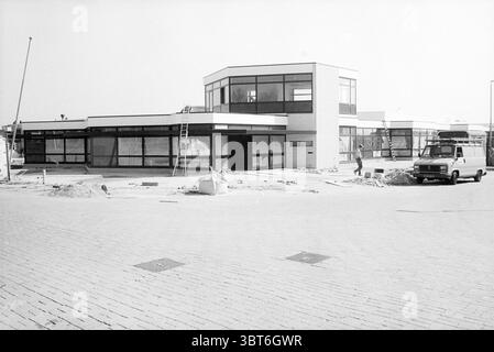 Edificio esterno di nuova costruzione di Huider Keukens Velserbroek Wagenmakerstraat, Whizgle News, Dutch Desk, Paesi Bassi, 1950 - 2000 il 30-03-1999. Questi sono gli argomenti nell'immagine. La scena cattura una struttura architettonica moderna caratterizzata da linee pulite e un design minimalista. L'edificio presenta grandi finestre di vetro che consentono un'atmosfera luminosa e spaziosa all'interno. Le pareti esterne sono principalmente bianche, in contrasto con la cornice nera delle finestre, a creare un aspetto nitido e contemporaneo. In primo piano, c'è un'atmosfera da cantiere, evidente attraverso la materia sparsa Foto Stock