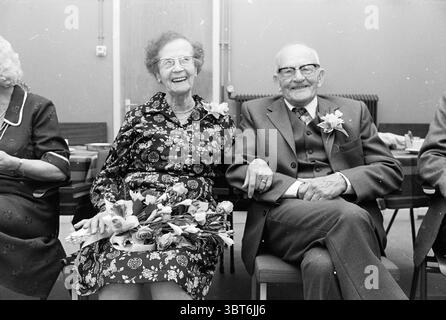 Donselaar coppia sposato per 65 anni matrimonio, Whizgle News, Dutch Desk, Paesi Bassi, 1950 - 2000 il 20-11-1978. Questi argomenti vengono visualizzati nell'immagine. In un ambiente interno illuminato da calore, una coppia siede fianco a fianco, trasudando un senso di gioia e compagnia. La donna, che indossa un abito floreale scuro con motivi vivaci, ha i suoi capelli ricciolati, donandole un aspetto classico e senza tempo. Possiede un bouquet di fiori, probabilmente freschi, che aggiunge un tocco di colore e simboleggia la festa. Accanto a lei, l'uomo è vestito con un abito grigio formale con un gilet, completato da una cravatta ben legata. Suo Foto Stock