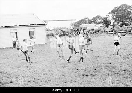 Parco giochi di calcio Vijfhuizen. Football, Whizgle News, Dutch Desk, Paesi Bassi, 1950 - 2000 il 06-08-1966. L'immagine contiene questi argomenti. In un ambiente all'aperto erboso, diversi bambini giocano con gioia e catturano durante la corsa e il salto. La scena è vivace, piena di energia e risate. I ragazzi e le ragazze variano in età e le loro espressioni rivelano un senso di eccitazione e cameratismo. I bambini indossano un abbigliamento estivo casual, pantaloncini e t-shirt, con calzini alti al ginocchio. Alcuni di loro hanno le braccia alzate, suggerendo che potrebbero essere impegnati in un gioco o in un gioco Foto Stock