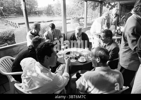 Cerimonia di premiazione per due persone con cena e band musicale, Whizgle News, Dutch Desk, Paesi Bassi, 1950 - 2000 il 06-1992. Questi argomenti sono mostrati nell'immagine. In un ambiente illuminato dal sole, un gruppo di uomini si riunisce intorno a un tavolo rotondo, impegnato in una conversazione vivace. L'atmosfera trasuda cameratismo e calore, caratterizzato da risate e gesti animati. Il tavolo è ricoperto di vari bicchieri, alcuni pieni di bevande chiare, mentre altri contengono tazze per la cottura a vapore, suggerendo un incontro informale, forse per un pomeriggio tranquillo. Gli uomini sono vestiti con un abbigliamento casual e semi-formale, con se Foto Stock