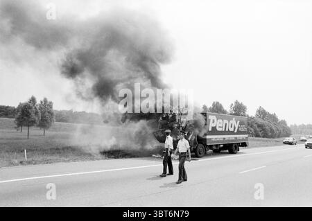 Camion al fuoco autostrada nazionale 9 uscita Heemskerk vigili del fuoco Heemskerk Rijksweg 9, Whizgle News, Dutch Desk, Paesi Bassi, 1950 - 2000 il 02-07-1986. Questi argomenti vengono visualizzati nell'immagine. La scena raffigura un momento teso su un'autostrada, in cui un grande camion è inghiottito di fumo nero, che si libra verso l'alto e crea un netto contrasto con il cielo altrimenti limpido. Il veicolo, con la parola "Pendy", è posizionato sul lato della strada, parzialmente oscurato dal fumo che emana dalla parte posteriore. In primo piano, due ufficiali in uniforme stanno in piedi, le loro espressioni sono serie come loro Foto Stock