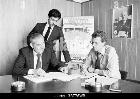 Presidente e membri degli ingegneri di volo Schiphol Personen Schiphol, Whizgle News, Dutch Desk, Paesi Bassi, 1950 - 2000 il 04-02-1982. L'immagine mostra questi argomenti. In un ufficio poco illuminato con pannelli in legno, tre persone sono impegnate in una discussione seria intorno a un tavolo lucido. La figura centrale, un uomo anziano vestito con un abito scuro, si siede intensamente, studiando una serie di documenti davanti a lui. Il suo comportamento suggerisce una profonda concentrazione, con una fronte solcata e un'espressione focalizzata. Alla sua destra, un uomo più giovane con i capelli ricci, con una camicia di colore chiaro e occhiali, scrive appunti Foto Stock