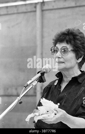 Lezione di cucina per bambini Haarlem Book City Cooking, Whizgle News, Dutch Desk, Paesi Bassi, 1950 - 2000 il 09-06-1979. L'immagine mostra questi argomenti. Una donna sta davanti a un microfono, impegnata a parlare con un pubblico. Ha un comportamento sicuro, con capelli corti e scuri che incorniciano il viso e occhiali rotondi che accentuano le sue caratteristiche espressive. Indossa una camicetta scura, che contrasta con il tono chiaro della sua pelle. L'ambiente sembra essere uno spazio interno, forse una sala o un auditorium, con uno sfondo neutro che suggerisce un ambiente semplice e funzionale. La l Foto Stock