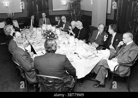 Letterary Dinner Coster Society at Brinkmann Passage Dinner, Whizgle News, Dutch Desk, Paesi Bassi, 1950 - 2000 il 11-03-1983. Questi argomenti vengono visualizzati nell'immagine. L'ambiente è una sala da pranzo formale, caratterizzata da un lungo tavolo rettangolare allestito elegantemente per un incontro. Il tavolo è ricoperto da un'immacolata tovaglia bianca, adornata con pregiate posate e bicchieri ordinatamente disposti in ogni posto. Al centro, una vivace disposizione floreale aggiunge un tocco di colore, caratterizzato da un mix di fiori disposti in un'esposizione lussureggiante e accattivante. Occupando la scena, un gruppo di individui ben vestiti Foto Stock