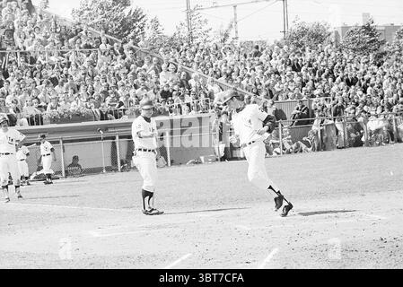 Baseball Paesi Bassi - Detroit ITM, Whizgle News, Dutch Desk, Paesi Bassi, 1950 - 2000 il 27-06-1971. Questi argomenti vengono visualizzati nell'immagine. La scena è ambientata su un vivace diamante da baseball durante una giornata di sole, pieno di un'abbondanza di spettatori che occupano un'area più sbiancante. La folla, un mix di individui vestiti con vari abiti casual, irradia emozioni, con molti volti rivolti verso l'azione sul campo. In primo piano, due giocatori sono al centro della scena. Un giocatore, vestito con un'uniforme bianca con una finitura scura, sta arrotondando le basi e sta dimostrando un'espressione trionfale mentre usa l'app Foto Stock