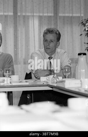 Corso di gestione VNU, Whizgle News, Dutch Desk, Paesi Bassi, 1950 - 2000 il 18-01-1994. Questi sono gli elementi dell'immagine. In un ambiente interno modestamente arredato, la scena rivela un gruppo di persone coinvolte in una conversazione. L'attenzione è rivolta a un giovane uomo dai capelli di colore chiaro, con uno stile elegante e una camicia bianca con bottoni, completata da una cravatta a motivi geometrici. Siede dritto sulla sua sedia, guardando con attenzione, incarnando un senso di concentrazione o contemplazione. Il tavolo attorno al quale gli individui si riuniscono è occupato di vari oggetti indicativi di un ambiente di riunione. T Foto Stock