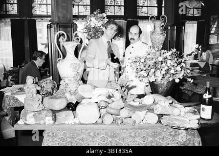 Ristorante Dorrius Amsterdam Restaurant, Whizgle News, Dutch Desk, Paesi Bassi, 1950 - 2000 su 11-10-1978. Questi argomenti sono mostrati nell'immagine. La scena cattura un'area pranzo elegantemente organizzata, con un ricco ambiente in legno accentuato da luce soffusa e naturale che filtra attraverso grandi finestre adornate con tessuti delicati. In primo piano, un lungo tavolo mostra un'impressionante varietà di prodotti alimentari, sia colorati che artisticamente esposti. Diversi piatti decorativi contengono una varietà di frutta, formaggi e pane artigianale, creando un vibrante contrasto con le sfumature del tablec Foto Stock