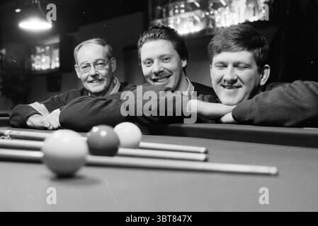Snooker academy Haarlem Three People Haarlem Paesi Bassi, Whizgle News, Dutch Desk, Paesi Bassi, 1950 - 2000 il 03-01-1994. Questi sono gli elementi dell'immagine. La scena presenta tre uomini che si appoggiano casualmente su un tavolo da biliardo, ognuno dei quali indossa maglioni scuri e accoglienti che contrastano con i toni più chiari dell'ambiente circostante. Le loro espressioni sono rilassate e gioviali, a indicare un senso di cameratismo. Il tavolo da biliardo, con la sua superficie verde in feltro, è adornato da diverse palline da biliardo colorate, tra cui rosse, gialle e bianche, posizionate ordinatamente in una formazione triangolare ad un'estremità Poll Foto Stock