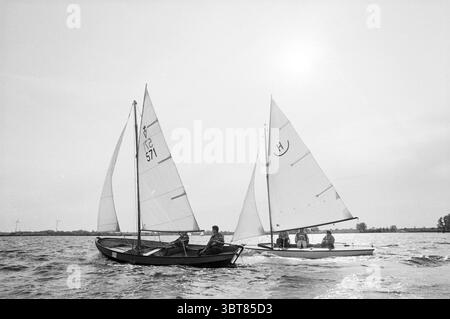 Gara di vela 24 ore Spaarne, Whizgle News, Dutch Desk, Paesi Bassi, 1950 - 2000 il 21-06-1991. L'immagine include questi argomenti. La scena presenta due piccole barche a vela che scivolano su un tranquillo corpo d'acqua, catturando un momento sereno di svago. Ogni barca, realizzata in legno scuro, ha una forma distintamente elegante, con le vele bianche che fluttuano graziosamente contro il vento. In primo piano, una barca è presidiata da due persone: Una si siede sul retro, l'altra naviga dal centro. Le loro figure sono sagomate sullo sfondo luminoso, sottolineando la loro postura rilassata come t Foto Stock