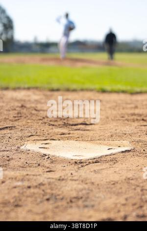 Lanciatore maschile e umpire senior che indossano uniformi in attesa sul campo da baseball vicino al piatto di casa e al tumulo Foto Stock