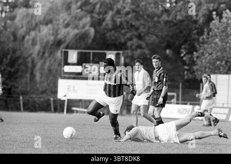 Football RCH - Ripperda, Whizgle News, Dutch Desk, Paesi Bassi, 1950 - 2000 il 11-11-1995. L'immagine mostra questi argomenti. La scena cattura un momento intenso in una partita di calcio. In primo piano, un giocatore con una maglia a strisce, principalmente nera con accenti rossi, sta avanzando con determinazione. La sua espressione facciale trasmette concentrazione e intensità, e la sua struttura muscolare suggerisce che è un atleta forte. Sul terreno nelle vicinanze, un avversario con una divisa di colore chiaro viene spazzato via, essendo caduto durante il gioco. Il linguaggio del corpo indica una lotta per riguadagnare posizione, forse dopo una virata Foto Stock