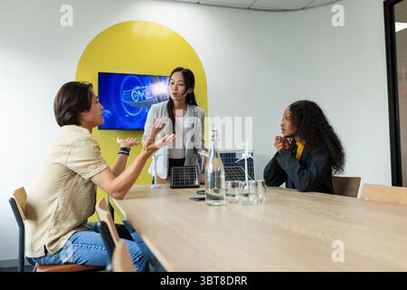 Diversi colleghi che presentano modelli di pannelli solari e turbine eoliche al moderno tavolo da conferenza per ufficio Foto Stock