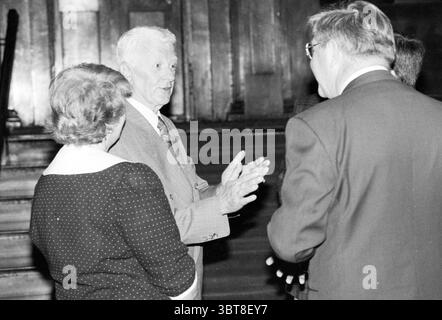 Addio Alderman Sikma Aldermen, Whizgle News, Dutch Desk, Paesi Bassi, 1950 - 2000 il 28-04-1990. L'immagine mostra questi argomenti. In uno spazio interno illuminato con pannelli in legno e una scala sullo sfondo, un piccolo gruppo di persone è impegnato in una conversazione. L'atmosfera generale sembra cordiale e intima. In primo piano, un uomo sta con una postura espressiva, le sue mani gestiscono animatamente mentre parla. Indossa un abito di colore chiaro e i suoi capelli argentati aggiungono un senso di saggezza o esperienza al suo aspetto. La sua espressione trasmette entusiasmo e cordialità. Accanto a lui, una W. Foto Stock