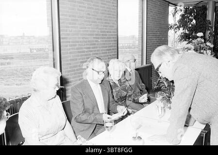 Anniversario Mr. Van Dijk Haarlems Dagblad Haarlems Dagblad ecc. e IJmuider Courant e Koeri Anniversary Anniversary Persons, Whizgle News, Dutch Desk, Paesi Bassi, 1950 - 2000 il 05-10-1981. L'immagine include questi argomenti. La scena presenta un gruppo di persone sedute su un lungo tavolo rettangolare in un ambiente luminoso e arioso. Le pareti sono costituite da grandi finestre, che consentono alla luce naturale di inondare e proiettare ombre morbide nello spazio. Il pavimento ha una texture sottile, possibilmente in tonalità chiare che completano l'atmosfera generale. Ad un'estremità del tavolo, un uomo con un vestito con vetro Foto Stock