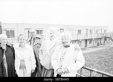 Cinque persone nella galleria di un complesso residenziale, Whizgle News, Dutch Desk, Paesi Bassi, 1950 - 2000 il 10-1989. L'immagine include questi argomenti. In un ambiente in bianco e nero, cinque individui stanno vicini, trasudando un senso di cameratismo. Le loro espressioni trasmettono un mix di calore e familiarità, suggerendo un'amicizia di lunga data o un legame familiare. Ogni persona presenta uno stile distinto: Uno si piega leggermente in avanti con un sorriso caldo, indossando un comodo cappotto di colore chiaro, mentre un altro, con un'elegante acconciatura, indossa una giacca sartoriale che aggiunge un tocco di raffinatezza. TH Foto Stock