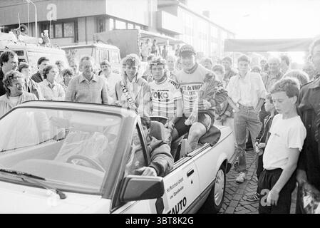 Vincitori dell'IJmuiden Cycling tour Cycling IJmuiden Paesi Bassi, Whizgle News, Dutch Desk, Paesi Bassi, 1950 - 2000 il 23-06-1985. L'immagine contiene questi argomenti. La scena cattura un'atmosfera vivace e vivace, incentrata su una cabriolet. Contro il veicolo c'è un gruppo di ciclisti, vestiti con vivaci maglie da corsa, adornati da vari loghi e sponsorizzazioni. Le loro espressioni irradiano entusiasmo e successo, suggerendo che hanno appena completato una gara o un evento significativo. La folla che li circonda è variegata e comprende spettatori di età e età diverse Foto Stock