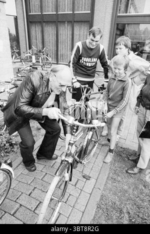Ispezione bicicletta Mosquito Round Mosquito Round, Whizgle News, Dutch Desk, Paesi Bassi, 1950 - 2000 il 01-08-1979. L'immagine include questi argomenti. In un vivace ambiente all'aperto, un piccolo gruppo di persone si riunisce intorno a una bicicletta, creando una scena coinvolgente piena di curiosità e interazione. Gli individui sono un mix di età, suggerendo una comunità o un incontro familiare. In primo piano, un uomo più anziano, distinto per la sua linea di capelli e gli occhiali, si appoggia sulla bicicletta, esaminandone con attenzione la meccanica. Indossa una giacca in pelle scura, che contrasta con i toni più chiari del TH Foto Stock