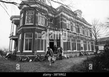 Gli squatters lasciano il vecchio hotel Beatrix Zijlweg Kraken Haarlem Zijlweg Paesi Bassi, Whizgle News, Dutch Desk, Paesi Bassi, 1950 - 2000 al 31-01-1984. Questi sono gli argomenti nell'immagine. La scena presenta un grande edificio in mattoni a due piani che trasuda uno stile architettonico vittoriano, caratterizzato da dettagli ornati e finestre multiple. La facciata e' caratterizzata da una combinazione di mattoni rossi e finiture bianche, fornendo un contrasto classico. Grandi finestre dominano la parte anteriore, riflettendo un'atmosfera silenziosa, probabilmente a causa del cielo coperto. Di fronte all'edificio, diverse persone sono impegnate in ACT Foto Stock