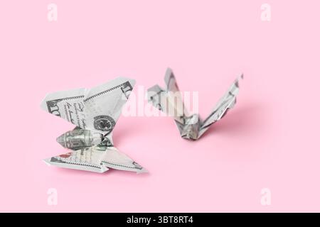 Farfalle Origami fatte di banconote in dollari su sfondo rosa, primo piano Foto Stock