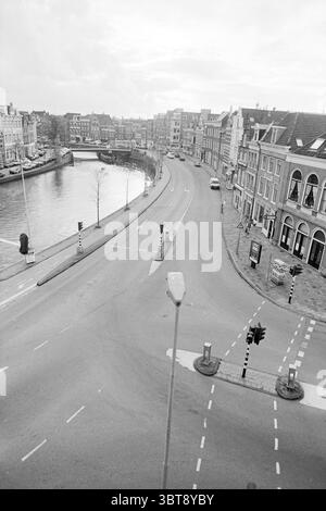 Vista di Damstraat Spaarne Haarlem Damstraat Paesi Bassi, Whizgle News, Dutch Desk, Paesi Bassi, 1950 - 2000 su 25-10-1994. Questi sono gli argomenti nell'immagine. La scena cattura un tranquillo paesaggio urbano caratterizzato da un tortuoso corso d'acqua che curva graziosamente lungo una strada. L'acqua riflette un cielo tenue, che lascia intendere le condizioni di copertura, mentre gli edifici che costeggiano la riva mostrano una serie di stili architettonici, contribuendo a creare un senso di fascino storico. La strada, priva di traffico pesante, è segnata da un veicolo isolato in lontananza e da una dispersione di segnali stradali Foto Stock