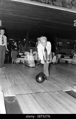 Inaugurazione del centro bowling IJmuiden inaugurazione delle aperture messe in uso, Whizgle News, Dutch Desk, Paesi Bassi, 1950 - 2000 il 24-01-1978. L'immagine mostra questi argomenti. In una vivace pista da bowling, l'attenzione è rivolta a un uomo pronto a lanciare una palla da bowling lungo la corsia. È vestito con un abbigliamento formale, completo di cravatta, in netto contrasto con l'atmosfera informale che lo circonda. La fronte è leggermente solcata, a indicare la concentrazione. La corsia stessa è una superficie in legno lucidato che riflette la luce ambientale degli apparecchi sopra la testa. Una palla da bowling nera lucida è in mano Foto Stock