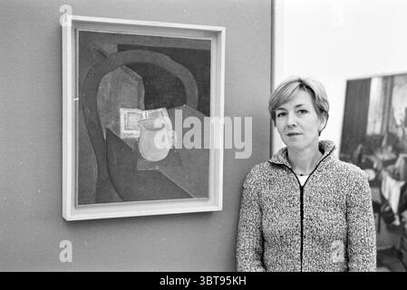Tre dipendenti del Frans Hals Museum e Verweyhal Haarlem Grote Markt Paesi Bassi, Whizgle News, Dutch Desk, Paesi Bassi, 1950 - 2000 il 05-12-1999. L'immagine include questi argomenti. In uno spazio interno minimalista, una donna si erge accanto a un'opera d'arte incorniciata esposta su una parete. Ha capelli corti e chiari e indossa un maglione grigio testurizzato che aggiunge un tocco di comfort alla scena. L'espressione sul suo volto appare contemplativa, suggerendo che potrebbe essere impegnata a pensare all'opera d'arte. L'opera d'arte stessa è una rappresentazione astratta, principalmente caratterizzata da toni tenui di marrone e beige Foto Stock