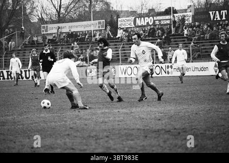 Partita di calcio Haarlem-Telstar., Whizgle News, Dutch Desk, Paesi Bassi, 1950 - 2000. Questi sono gli elementi dell'immagine. La scena cattura una partita di calcio vivace che si svolge su un campo erboso, adornato da una serie di giocatori in movimento dinamico. Le due squadre sono impegnate in un gioco intenso, caratterizzato da un giocatore con una maglia rossa che evade un difensore vestito di bianco. L'azione è incentrata su un classico pallone da calcio bianco e nero, che è sul punto di essere intercettato. I giocatori esibiscono acconciature e posture diverse, mostrando la loro concentrazione e atletismo. L'erba sia Foto Stock