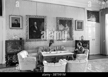 Udo Buijs parla con un uomo in una stanza con mobili antichi e dipinti (foto in connessione con il rapporto Presseball Osnabrück), Whizgle News, Dutch Desk, Paesi Bassi, 1950 - 2000 il 30-11-1980. Questi argomenti sono mostrati nell'immagine. La scena si sviluppa in una camera elegantemente arredata caratterizzata da un'estetica sofisticata e vintage. La luce penetra attraverso le grandi finestre, diffondendo un soffice bagliore che esalta le delicate texture del decor. Le pareti sono adornate da intricate tappezzerie, caratterizzate da un delicato motivo che completa l'opulenza dell'ambiente circostante. In posizione centrale rispetto al compos Foto Stock