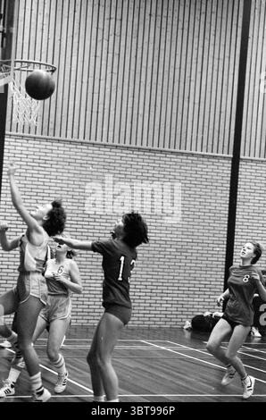 Partita di basket femminile, Whizgle News, Dutch Desk, Paesi Bassi, 1950 - 2000 il 15-12-1984. Questi argomenti sono mostrati nell'immagine. La scena cattura un momento dinamico in una partita di basket al coperto. Un gruppo di giovani atleti è impegnato in intense competizioni, mettendo in mostra sia l'energia che il lavoro di squadra intrinseco allo sport. In primo piano, due giocatori sono in primo piano. Uno, in uniforme leggera con il numero "6", sta facendo un salto deciso verso il cerchio, i capelli volano e le braccia che si avvicinano verso l'alto, con una pallacanestro che le lascia le dita. La sua espressione trasmette concentrazione ed effo Foto Stock