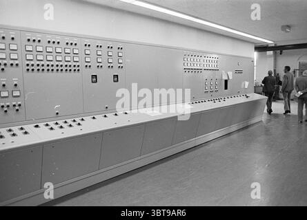 Fognatura impianto di trattamento delle acque fognarie, Whizgle News, Dutch Desk, Paesi Bassi, 1950 - 2000 il 21-07-1976. Questi argomenti vengono visualizzati nell'immagine. La scena presenta un interno spazioso incentrato su un ampio pannello di controllo grigio che si estende su una parete. Questo pannello è progettato meticolosamente e presenta una serie di pulsanti, interruttori e spie. I bottoni variano nelle dimensioni e nei colori, con molti che appaiono in toni tenui di beige e argento, suggerendo un'estetica utilitaria. Alcune luci si illuminano dolcemente, suggerendo attività, mentre altre rimangono scure, creando un contrasto che attira l'attenzione. A sinistra di Foto Stock