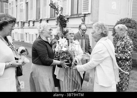 Antica parata ricevimenti reali e visite reali, Whizgle News, Dutch Desk, Paesi Bassi, 1950 - 2000 il 13-06-1978. L'immagine include questi argomenti. In una vivace scena all'aperto, un gruppo diversificato di individui si riunisce intorno a una donna che ha una grande disposizione floreale, traboccante di fiori e vegetazione varie. La donna che riceve il bouquet è vestita con un cappotto di colore chiaro, il suo viso irradia gioia e apprezzamento mentre sorride in grande. Il bouquet, una vivace raffica di colori, contrasta splendidamente con i toni più tenui dell'abbigliamento e dell'architettura circostante. Alla sua sinistra, un OL Foto Stock