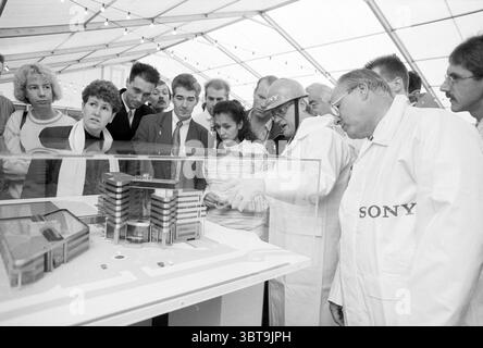 Primo pile Sony Badhoevedorp Badhoevedorp, Whizgle News, Dutch Desk, Paesi Bassi, 1950 - 2000 il 04-11-1990. Questi sono gli argomenti nell'immagine. In una tenda spaziosa e luminosa, un gruppo diversificato di individui si riunisce intorno a un espositore trasparente con un modello architettonico dettagliato. Il modello raffigura un moderno edificio a più piani, che rappresenta probabilmente una struttura aziendale o commerciale, con linee eleganti e grandi finestre in vetro. La scena è piena di emozioni; alcuni partecipanti sembrano curiosi e impegnati, si avvicinano per ispezionare il modello, mentre altri mantengono un'immagine più precisa Foto Stock