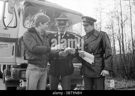 Polizia nazionale al lavoro Halfweg polizia Halfweg, Whizgle News, Dutch Desk, Paesi Bassi, 1950 - 2000 il 20-02-1980. L'immagine contiene questi argomenti. In un ambiente che sembra essere lungo la strada o in un'area remota, tre persone sono impegnate in una conversazione vicino a un veicolo di grandi dimensioni che ha un aspetto industriale. Due di queste persone sono vestite con uniformi oscure della polizia, complete di cappelli con insegne, che suggeriscono di essere agenti delle forze dell'ordine. Il terzo individuo, un giovane con i capelli tondi, è vestito con una giacca e un denim casual di colore chiaro, che contrasta con il formale Foto Stock