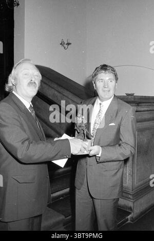 Presentazione del Premio L.J. Coster Presentation, Whizgle News, Dutch Desk, Paesi Bassi, 1950 - 2000 il 01-11-1985. Questi sono gli argomenti nell'immagine. In questa scena, due uomini stanno vicini, impegnati in un momento di riconoscimento o celebrazione. Entrambi sono vestiti con un abbigliamento formale, con un uomo che indossa un abito scuro e una cravatta che include un motivo sottile, mentre l'altro ha un vestito più leggero e una cravatta che contrasta con l'abbigliamento più scuro del suo compagno. Il primo uomo trasuda un'aria di autorità o onore, con i capelli del viso e un'espressione che suggerisce orgoglio. Si allunga la mano, tenendo un SM Foto Stock