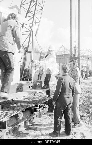 1° post Nieuw-Vennep primo post, Whizgle News, Dutch Desk, Paesi Bassi, 1950 - 2000 il 21-10-1971. Questi argomenti sono mostrati nell'immagine. La scena si sviluppa in un cantiere, caratterizzato da una combinazione di macchinari industriali e lavoratori attivi. In primo piano, un gruppo di quattro uomini si trova vicino a un grande pezzo di macchina, forse una gru. Due uomini sono impegnati nell'atto di salire sull'attrezzatura, uno con un elmetto bianco e un cappotto di colore chiaro. Il suo volto è diretto verso i comandi all'interno della macchina, suggerendo di concentrarsi sul suo funzionamento. L'uomo che lo assiste indossa un buio Foto Stock