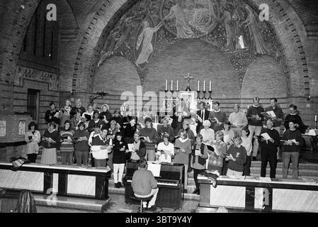 Chiesa del Coro Valkenburgerplein H'stede Heemstede Valkenburgerplein Nederland, Whizgle News, Dutch Desk, Paesi Bassi, 1950 - 2000 il 30-10-1994. Questi sono gli argomenti nell'immagine. In un grande spazio a più archi adornato da intricati murales, un grande gruppo di individui si trova in file organizzate, chiaramente impegnati in una performance corale. La scena è piena di un senso di unità e di scopo, emanando un'atmosfera di riverenza e concentrazione. I membri del coro, un mix di età e sfondi diversi, sono vestiti con una varietà di abiti comodi, con molti che indossano maglioni e camicette Foto Stock