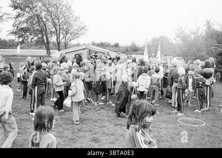 Pedalò a Lisse + giochi per bambini a Beeckestijn Children's Houses Children's Party Children's, Whizgle News, Dutch Desk, Paesi Bassi, 1950 - 2000 il 21-09-1974. Questi sono gli argomenti nell'immagine. La scena è piena di attività e mostra un grande gruppo di bambini riuniti in un ambiente all'aperto. Sono prevalentemente vestiti con tute coordinate, contribuendo a un flusso visivo uniforme. Le tute sono un mix di colori, tra cui sfumature di blu, rosso e verde, che donano un'atmosfera vivace nonostante il cielo coperto. Sullo sfondo, si aprono diverse tende, suggerisco Foto Stock