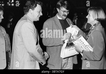 Presentazione Ufficio Provinciale del turismo Olanda settentrionale, Whizgle News, Dutch Desk, Paesi Bassi, 1950 - 2000 il 20-10-1993. L'immagine include questi argomenti. In una scena vivace, tre persone si impegnano in una conversazione, trasudando un'aria di familiarità e calore. L'ambientazione sembra essere un evento serale, forse un raduno o una celebrazione, caratterizzato da un'illuminazione soffusa che proietta ombre delicate e mette in risalto le loro espressioni. A sinistra, una donna con un blazer di colore chiaro sorride composto, i suoi capelli sono stati modellati con cura. Si e' posizionata leggermente lontano dall'interazione principale, ob Foto Stock