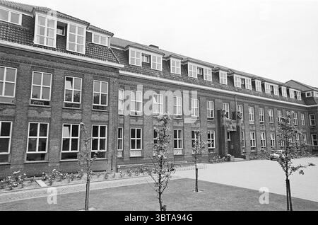 Mission House Driehuis Buildings IJmuiden Velsen, Whizgle News, Dutch Desk, Paesi Bassi, 1950 - 2000 il 09-07-1965. L'immagine contiene questi argomenti. La scena raffigura un grande edificio in mattoni a due piani caratterizzato da file ordinate di finestre. La struttura presenta un design architettonico tradizionale, con una facciata simmetrica caratterizzata da più pannelli in ogni finestra. Il tetto è inclinato e rifinito con piastrelle a motivi geometrici, conferendogli un aspetto classico. Di fronte all'edificio sono presenti macchie di erba ben tenute, intervallate da piccoli alberi che aggiungono un tocco di verde. Il paesaggio appe Foto Stock