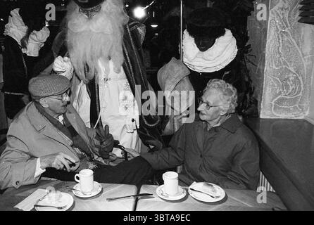 Le persone disabili fanno acquisti a V&D, Whizgle News, Dutch Desk, Paesi Bassi, 1950 - 2000 il 20-11-1995. Questi argomenti vengono visualizzati nell'immagine. L'ambiente e' un intimo spazio interno, magari un caffe' o un ristorante, con un'atmosfera calda. L'illuminazione è tenue ma invitante, creando una luce soffusa che mette in risalto la scena senza essere dura. In primo piano, due persone anziane sono sedute ad un tavolo di legno. Sono impegnati in una conversazione, condividendo un momento di connessione. L'uomo indossa un berretto a motivi geometrici e un cappotto leggero, che mostra un'espressione acuta mentre parla. La sua compagna, una donna dai capelli grigi, fa sport Foto Stock