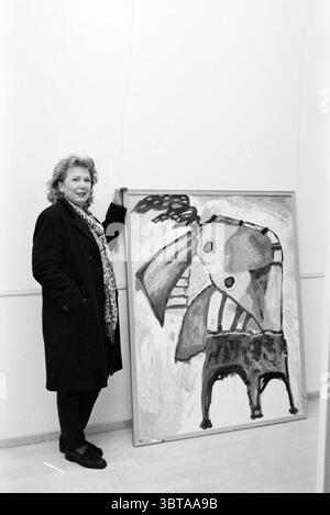 Tre dipendenti del Frans Hals Museum e Verweyhal Haarlem Grote Markt Paesi Bassi, Whizgle News, Dutch Desk, Paesi Bassi, 1950 - 2000 il 05-12-1999. L'immagine contiene questi argomenti. In una galleria minimalista, una donna si trova accanto a una grande opera d'arte astratta. Ha un sorriso caldo ed è vestita con un lungo cappotto nero, che trasuda eleganza. Una sciarpa a motivi geometrici aggiunge un tocco di personalità al suo abbigliamento. L'opera d'arte presenta tratti e forme audaci, combinando sfumature di tonalità naturali come marrone, crema e rosso tenue. La composizione trasmette sia il caos che la struttura, con forme geometriche Foto Stock